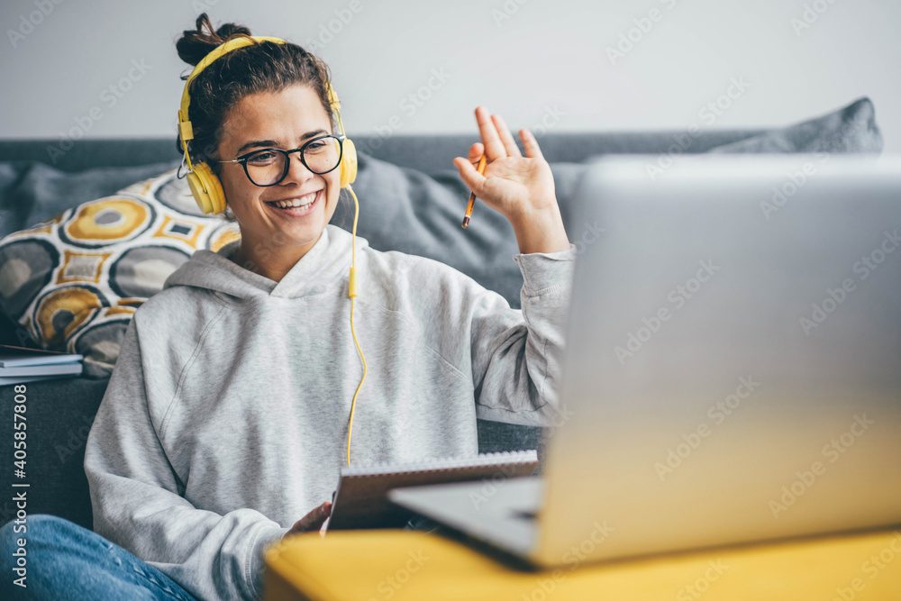 Millennial woman having video call on her computer at home. Smiling girl studying online with teacher.